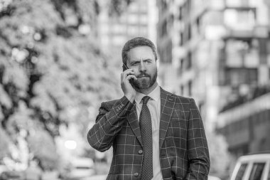 Kafkasyalı işadamının sokakta telefon görüşmesi var. İş adamı dışarıda telefon ediyor. İş adamının telefonla arayıp konuştuğu fotoğraf. İş adamının dışarıda telefonu var..