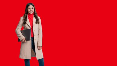 Genç kız dizüstü bilgisayarı tutuyor. Online eğitim. Okula dönelim. Bilgi ve çevrimiçi eğitim. Dizüstü bilgisayarda video dersi. Uzay afişini kopyala. Dizüstü bilgisayarı olan genç kız kırmızıda izole edilmiş..