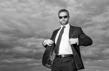 Kaygısız iş adamı gökyüzü arka planında fotokopi uzayı ile. Takım elbiseli kaygısız bir iş adamı. Takım elbiseli kaygısız bir iş adamı. Tasasız iş adamının takım elbiseli fotoğrafı..