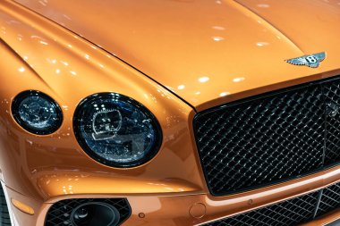 New York City, ABD - 27 Mart 2024: Bentley Continental GT lüks araba farları ve New York Uluslararası Otomobil Fuarı logosu, yakın görüş.