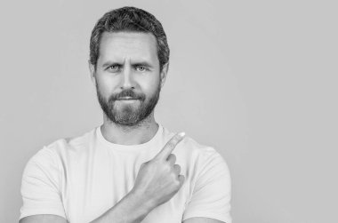 Arka plandaki reklam teklifini işaret eden bir adamın portresi. Stüdyodaki reklam teklifini işaret eden adam. Reklam teklifini işaret eden adamın fotoğrafı. Adam reklam teklifini işaret ediyor.