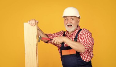 Sarı arka planda, miğferli kıdemli marangoz.