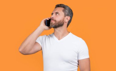 Düşünen adam iletişim akıllı telefonunda konuşur. Adam akıllı telefon konuşmaları yapıyor. İletişim konsepti. Akıllı telefondan konuşan adam sarıda izole edilmiş. Stüdyoda adam akıllı telefonda konuşur..