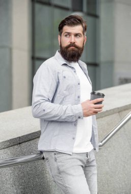 Sakallı adam dışarıda kahve içiyor. Adam sokakta kahve içiyor. Kahve içen bir adamın fotoğrafı. Adam dışarıda kahve içiyor..