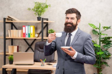Mutlu sakallı işadamı ofiste fotokopi yeri olan kahve içiyor..