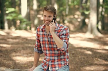 Kareli gömlekli genç adam telefonda konuşuyor..