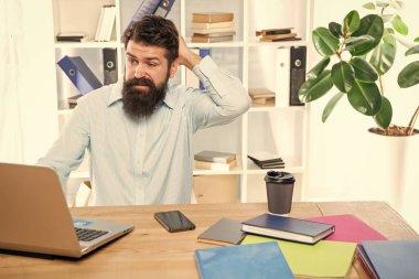 Ofiste dizüstü bilgisayar başında çalışırken kafası karışmış bir işadamı kafası karışıyor..