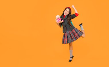 Sarı arka planda oyuncağı olan okul üniformalı mutlu çocuk, Eylül.