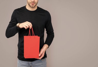 Stüdyodaki alışveriş çantalı adamın görüntüsü. Alışverişten sonra adam. Alışveriş yapan adam alışveriş torbasında bekliyor. Alışveriş torbası alımı gri arka planda izole edilmiş..