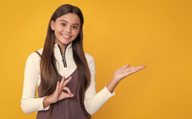 Sarı arka planda uzun saçlı, gülümseyen bir çocuk. ürün sunuluyor.