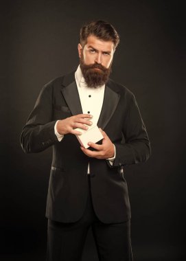 Smokin giymiş ciddi bir adam siyah arka planda hediye kutusuyla resmi kravat takıyor. Boks günü.