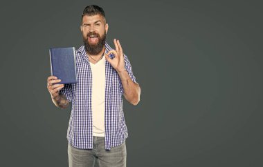 Sakallı adam gri arka plan hakkında kitap tavsiye eder. Tamam.