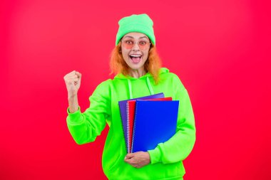 Üniversitenin kadın öğrencisi, pembe üzerine izole edilmiş okul kitabıyla bilgi ve eğitim alıyor..