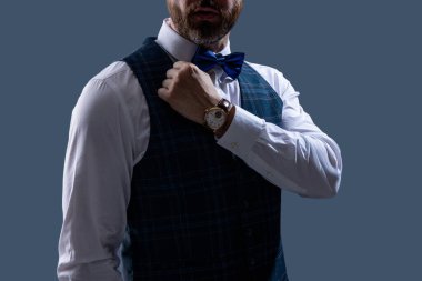 Erkek aksesuarı. Papyonlu beyefendi lüks saat gösteriyor. Pahalı bir kol saati. Papyonlu adam ve saat. Zarif saat aksesuarı. Zaman doldu. Gri renkte soyutlanmış zarif beyefendi..