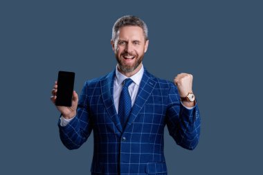 Griler 'de izole edilmiş bir telefon gösteren bir iş adamı. Takım elbiseli adam. Yeni telefon uygulaması. Ürünü sunuyorum. İş uygulamasının reklamı. İspanyol iş adamı telefon ekranını sunuyor. Başarı kutlaması.