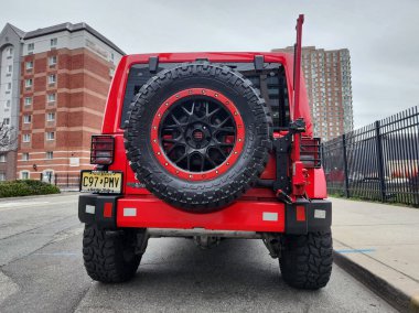 New York, ABD - 22 Mart 2024: 2015 Jeep Wrangler Sınırsız Sahara kırmızı arabası, arka manzara.