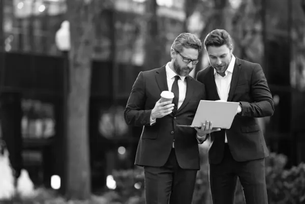 Stock image photo of businessmen trading online, banner. two businessmen trading online. businessmen trading online outdoor. businessmen trading online with laptop.