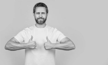 Adam sarı renkte izole edilmiş, kopyalama alanı. Adam arka planı onaylıyor. Adam stüdyoyu onaylıyor. Onaylanmış bir adamın fotoğrafı. Baş parmağıyla..