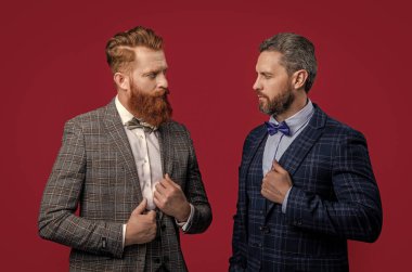 Papyonlu, resmi smokinli, beyaz, zarif erkekler. Papyonlu smokinli adamlar bordo arka planda izole edilmiş. Smokin papyonlu iki adam. Stüdyoda papyon ve smokin giyen adamlar..