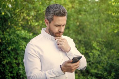 İnternette telefon işi yapan pazarlama işadamı. Telefonlu pazarlama işadamının fotoğrafı. Telefonlu pazarlama işadamı. Açık havada telefonu olan pazarlama işadamı..