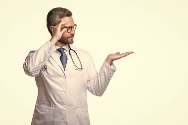 Doktor arka planda fotokopi alanı olan bir ürün sunuyor. Kardiyolog erkek doktorun fotoğrafı. Doktor beyazı izole etti. Stüdyoda doktor.