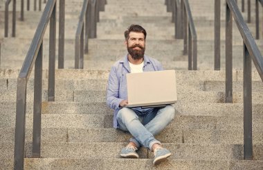 Gülümseyen serbest çalışan adamın dışarıda bilgisayarı var. Serbest çalışan bir adamın sokakta bilgisayar bağlantısı var. Dizüstü bilgisayarı olan serbest çalışan bir adam. Serbest Çalışan Adam 'ın online bilgisayar iletişimi var.