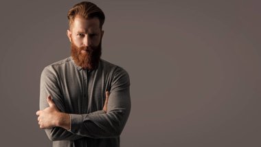 Gri arka planda sakallı ve bıyıklı traşsız adam, kopyalama alanı. Traşsız adamın stüdyo çekimi. Bıyık ve sakal bakımı. Tıraşsız yakışıklı adamın sakalı ve bıyığı var..