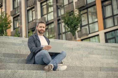 Dışarıda bilgisayar olan serbest çalışan adam için kopyalama alanı. Bilgisayarlı serbest çalışan adamın fotoğrafı. Dışarıda dizüstü bilgisayarı olan serbest çalışan bir adam. Sokaktaki serbest çalışan adam..