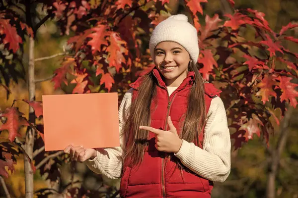 stock image best offer for season. autumn offer sale. teen girl make an offer. girl offering advertisement in autumn nature. fall seasonal discount. offering autumn tips. school time in fall. pointing finger.