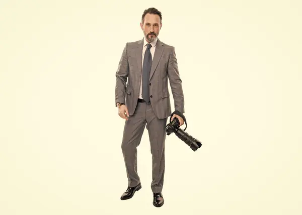 stock image businessman hold photo camera. photojournalist in business suit. business photographer with camera. journalist man taking photo isolated on white. paparazzi photographer in full length.