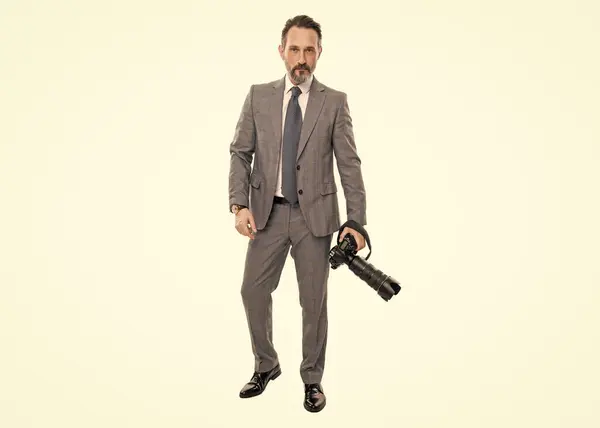 Stock image businessman hold photo camera. photojournalist in business suit. business photographer with camera. journalist man taking photo isolated on white. paparazzi photographer in full length.