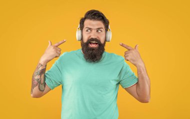 Hippi kulaklıklı adam müzik dinliyor. Kulaklıklı hipster adamın stüdyo fotoğrafı. Müzik dinliyordum. Modern erkek aleti. Kulaklıkla müzik dinleyen hippi adam sarıda izole edilmiş..