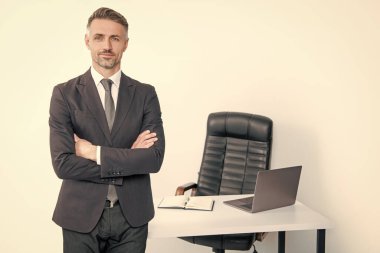 Olgun adam patron ofisinde beyaz arka planda takım elbise giyer..