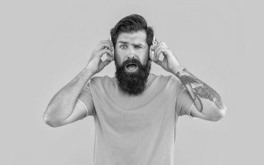 Sinirli adamın sarı kulaklıklarda yüksek sesli müziği var. Sinirli adam kulaklıkla yüksek sesle müzik dinler. Yüksek sesli kulaklıklı rahatsız bir adam. Yüksek sesli müzikle rahatsız bir adamın stüdyo çekimi..