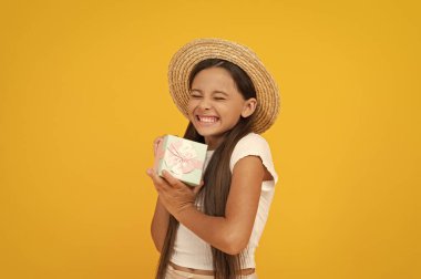 Mutlu genç çocuk hediye kutusunu sarı arka planda tutuyor..