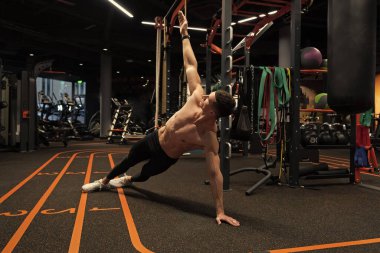 Spor salonunda kaslı adam yan tahta egzersizi yapıyor. Beden eğitiminde yan tahta egzersizi. Spor ve spor. Spor salonundaki kaslı adam egzersizi..