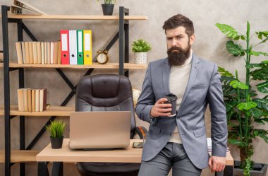 Takım elbiseli, çay ya da kahve içen, ofis masasında oturan ciddi bir yönetici..