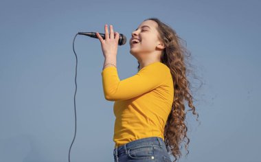 happy teen girl singing karaoke in microphone.