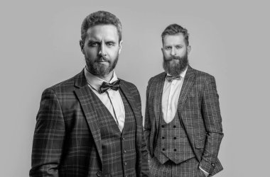 Resmi smokinli, papyonlu, seçici odaklı zarif erkekler. Papyonlu smokinli adamlar gri arka planda izole edilmiş. Smokinli iki adam papyon takıyor. Stüdyoda papyon ve smokin giyen erkeklerin fotoğrafları..