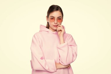 Serious young woman in casual pink hoodie and glasses isolated on white, girl.