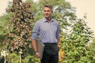 cheerful man hold laptop. man freelancer outdoor. business man with pc.