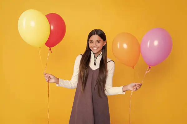 stock image happy child with party colorful balloons on yellow background.