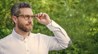 Gözlüklerle mesafeye bakan profesyonel bir adamın portresi doğal arka plan, kopyalama alanı.