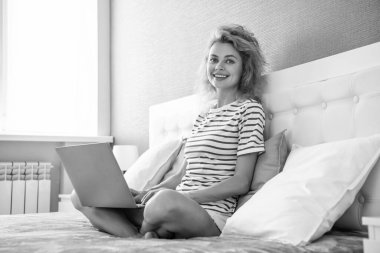 Evdeki neşeli kadının bilgisayarında görüntülü arama var. Kadının görüntülü aramayla iletişimi var. Video iletişimi. Yatakta dizüstü bilgisayarlı bir kadın.