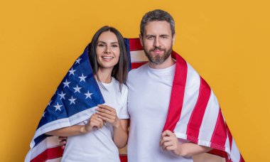 Öğrenci bir çift Amerikan bayrağıyla gururla poz veriyor. Amerikan bayrağı taşıyan çiftlerin vatanseverliği. Bayrağa sarılı Amerikalı ruh çifti kutluyoruz. Bayrağı olan Amerikalı çift..