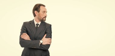 Kendine güvenen gri saçlı ciddi iş adamı patronunun profil portresi. Resmi bir iş elbisesi stüdyosunda kollarını kavuşturuyor. Beyazlar içinde izole edilmiş..