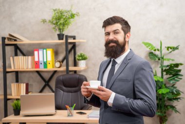 İş adamı kılığındaki neşeli acımasız CEO ofiste sabah kahvesini yudumluyor, iş adamı..