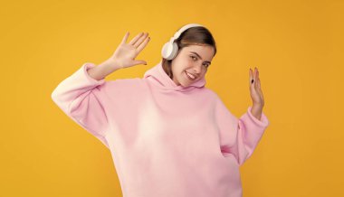 smiling young girl listen music in headphones on yellow background.