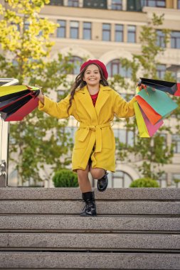 Alışveriş torbaları açık havada alışveriş yapan bir genç. Sonbahar montlu genç kız. Sonbahar alışverişçisi kız şehirde butikleri keşfediyor. Sonbahar alışverişçisi kız gardırobunu mevsimlik satışlarla değiştiriyor. Alışveriş bölgesi.