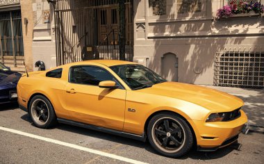 New York City, ABD - 05 Ağustos 2023: 2011 Ford Mustang V6 sarı araç yan görüntüsü, park edilmiş.